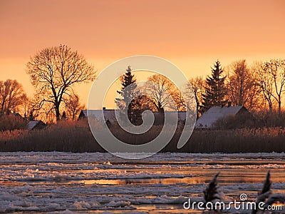 River Atmata , homes and snowy trees in sunset colors, Lithuania Stock Photo