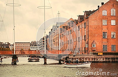 River boat and cityscape with old buildings over water in Copenhagen, Denmark. Danish capital under clouds Stock Photo