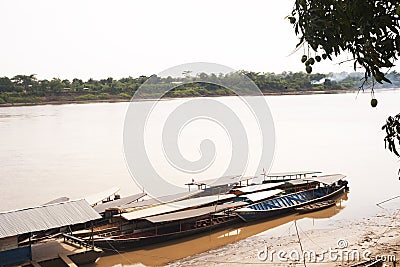 River Boats tied up to pier along river bank with view to other shore in Puerto Maldonado in Peru and the Amazon Stock Photo