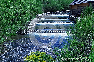 River cascading among green forest and wooden house Stock Photo