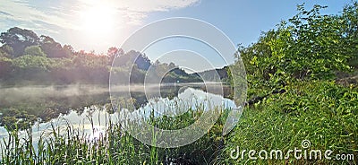 river is covered with fog at dawn. Forest is reflected in the river in summer Stock Photo