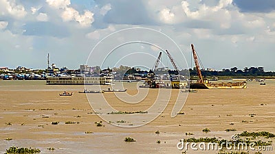 River cranes boats barges sand traffic Cambodia Editorial Stock Photo