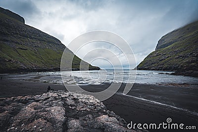 River delta with black sand beach, rocks and high cliffs in Faroe islands, close to village Saksun in Faroese island Stock Photo
