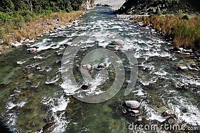 A river flowing through forested valley of Himalaya,Arunachal Pradesh,India.Sunny morning with blue sky.River flow through rocks Stock Photo