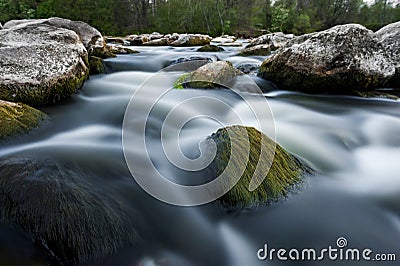 River flows among the stones. Blurry water. Stock Photo