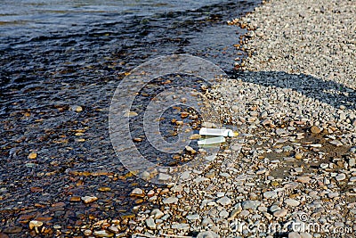 River pollution near the shore, garbage near the river, plastic food waste, contributing to pollution Stock Photo