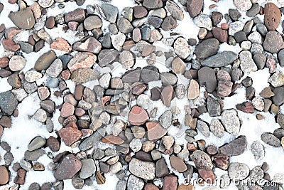 River rock gravel mulch in grey and red colors in winter with a light covering of snow Stock Photo