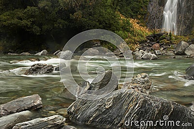 River with rocks, milky water, and waterfall Stock Photo