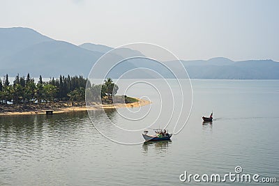 River scene in Vietnam, with fishing boat, strip of land and mountain on background Editorial Stock Photo