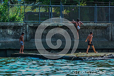 River view of little boys playing at the bay. Children jumping into the water. Editorial Stock Photo