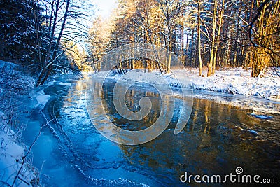 River in winter. Dappled sunlight streaming in mixed forest Stock Photo