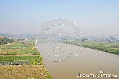 Riverside cultivated farmland in sunny foggy winter morning Stock Photo