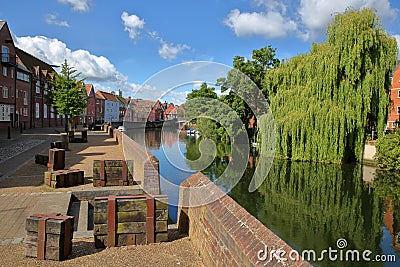 The riverside river Wensum in Norwich Norfolk, UK with colorful houses on the left side and the Fye Bridge in the background Stock Photo