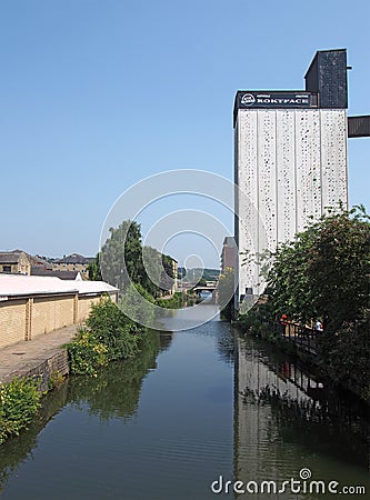 Riverside view of brighouse town with the former sugdens flour mill and grain silo now a large outdoor climbing wall and adventure Editorial Stock Photo