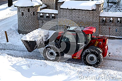 RIVNE, UKRAINE - FABRUARY 16, 2021. Removing snow from the streets with a tractor. A bulldozer with a bucket clears snow from the Editorial Stock Photo