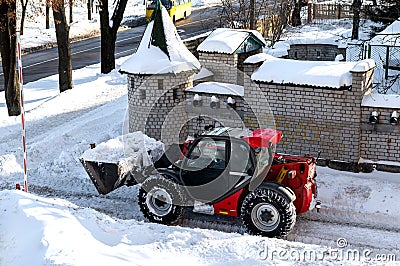 RIVNE, UKRAINE - FABRUARY 16, 2021. Removing snow from the streets with a tractor. A bulldozer with a bucket clears snow from the Editorial Stock Photo