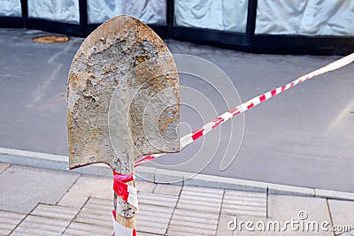 Road blocked for repair. Line stop tape tied to an old spade Stock Photo