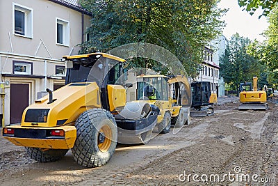 Road construction equipment: excavators, asphalt rollers, bulldozers on a city street with the road surface removed Stock Photo