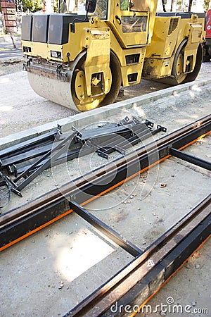 Road construction site with tram rail and steel drum roller Stock Photo