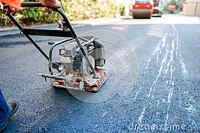 Road construction with worker paving the fresh bitumen or asphalt Stock Photo