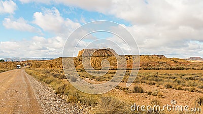 Road at a desert with a view of a monolith under a cloudy sky Stock Photo