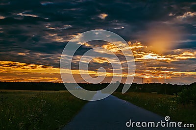 Road in the field at sunset. Summer field. Asphalt road. Summer landscape. Russian roads Stock Photo