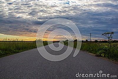 Road in the field at sunset. Summer field. Asphalt road. Summer landscape. Russian roads Stock Photo