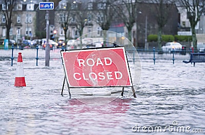 Road flood closed sign under deep water during bad extreme heavy rain storm weather in UK Stock Photo