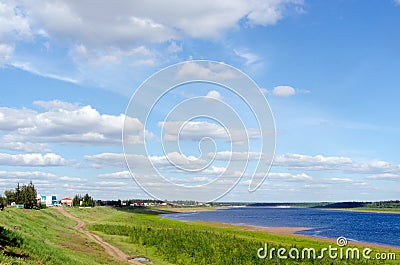 The road goes along the shore North of the river Vilyuy in the second half of the day near the houses of the village of Suntar. Stock Photo