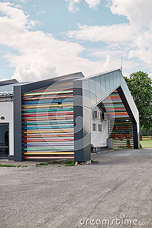 Road with modern building with beautiful creating wall with multicolored colorful wooden rails on facade Stock Photo