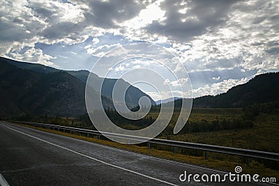 Road in mountains valley and storm clouds on a dark sky Stock Photo