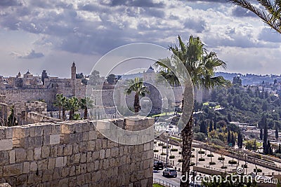 The road, palm trees, and garden around the fortress walls of the Old Town of Jerusalem in Israel. Stock Photo