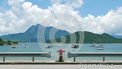 Road, red water pump, boat, tree, lake, blue sky Stock Photo