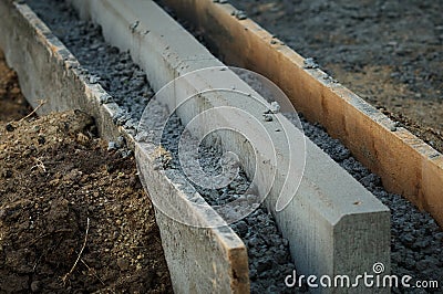 Road repair, installation of curbs. Laying a new border. The end face of a stone filled with concrete mixture close up Stock Photo