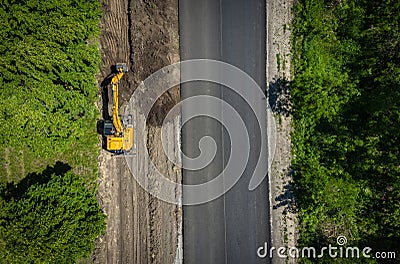Road repairs. Excavator bucket removes soil along the roadbed Stock Photo