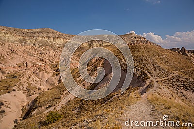 The road in the rocks in the Rose valley, Gulludere valley. In the distance White mountain, Aktepe hill. Cappadocia, Anatolia, Stock Photo