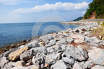 A road running at the side of water under blue sky. Stock Photo