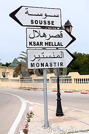 Road sign with directions to Monastir, Sousse and Ksar Hellal is in town of Tunisia. English and Arabic inscriptions. Africa Stock Photo