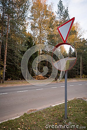 Road sign - give way and outdoor convex protective mirror with a reflection of the urban road look car Stock Photo