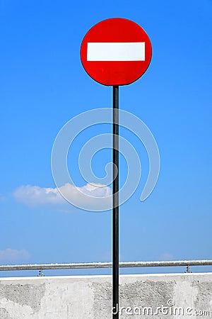 Road sign on a metal pole `Do not enter` sign against a blue sky with white clouds background. Stock Photo