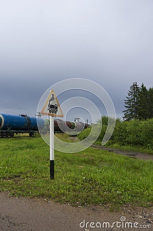Road sign `Railway crossing without barrier` with oil tanks Stock Photo