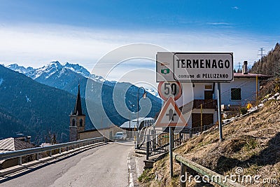 Road sign of small village Termenago, Trento, Italy. Buildings and snow-capped Italian mountains. Stock Photo