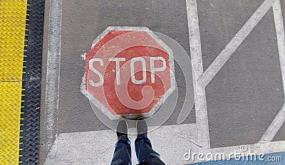 Road sign `Stop` painted on road with two standing feet in front Stock Photo