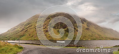 Road signs Leenaun and Louisburgh by a road. Beautiful scenery in the background. Mountains and low clouds and a lake. Connemara, Stock Photo