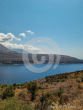 Road to Limeni village with fishing boats in turquoise waters and the stone buildings as a background in Mani, Greece Stock Photo