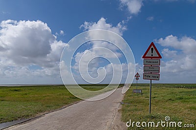 The road to MandÃ¸, Denmark with warning sign of tidal water Stock Photo