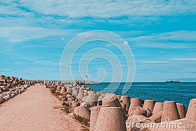 Road to a pier with a lighthouse, along the edges of the breakwater in Ventspils, Latvia Stock Photo
