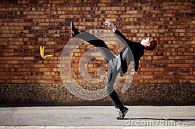 The road to success is a slippery one at best. A young businessman slipping on a banana peel. Stock Photo