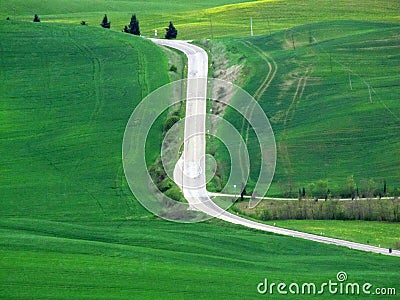 Road uphill with curves, in the Tuscan countryside, with other signs in the green, of paths and roadways Stock Photo