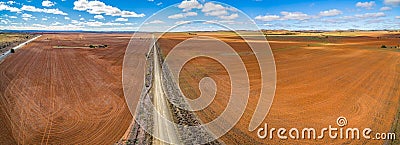 Road vanishing into the horizon between plowed fields. Stock Photo